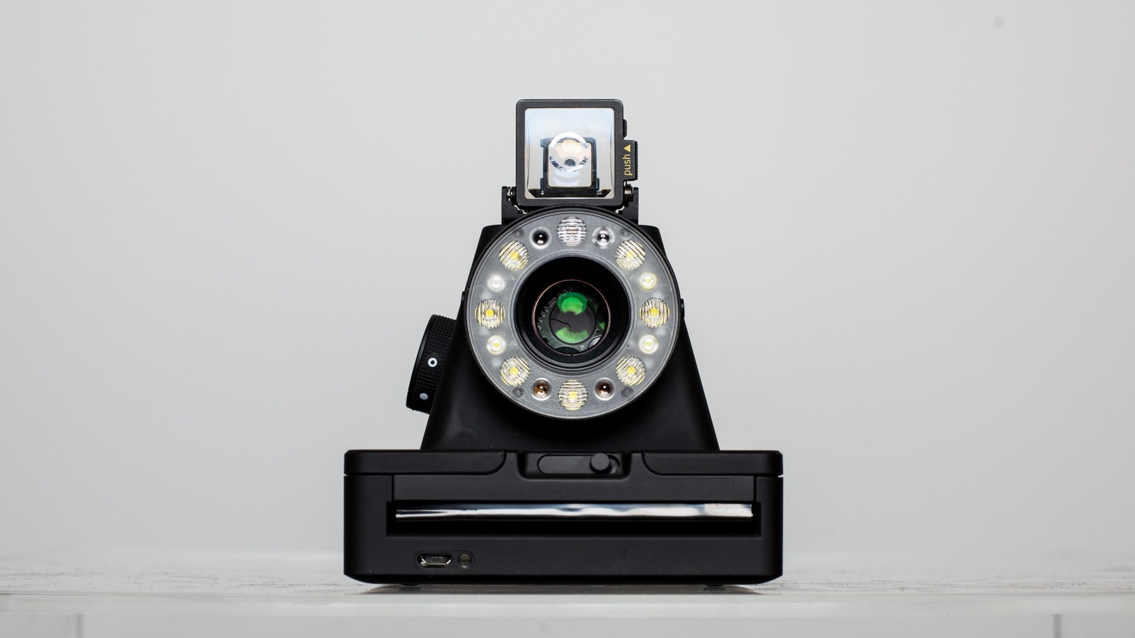 There is a camera that is sitting on a stand with a light on (camera, camera lens, cameras optics, camera accessory, digital cameras)