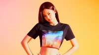 Jennie Kim de BLACKPINK dans un t-shirt cropped stylé de Calvin Klein, posant devant un fond dégradé vibrant.