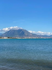 Serene Lakeside Landscape with Majestic Mountains and Cumulus Clouds