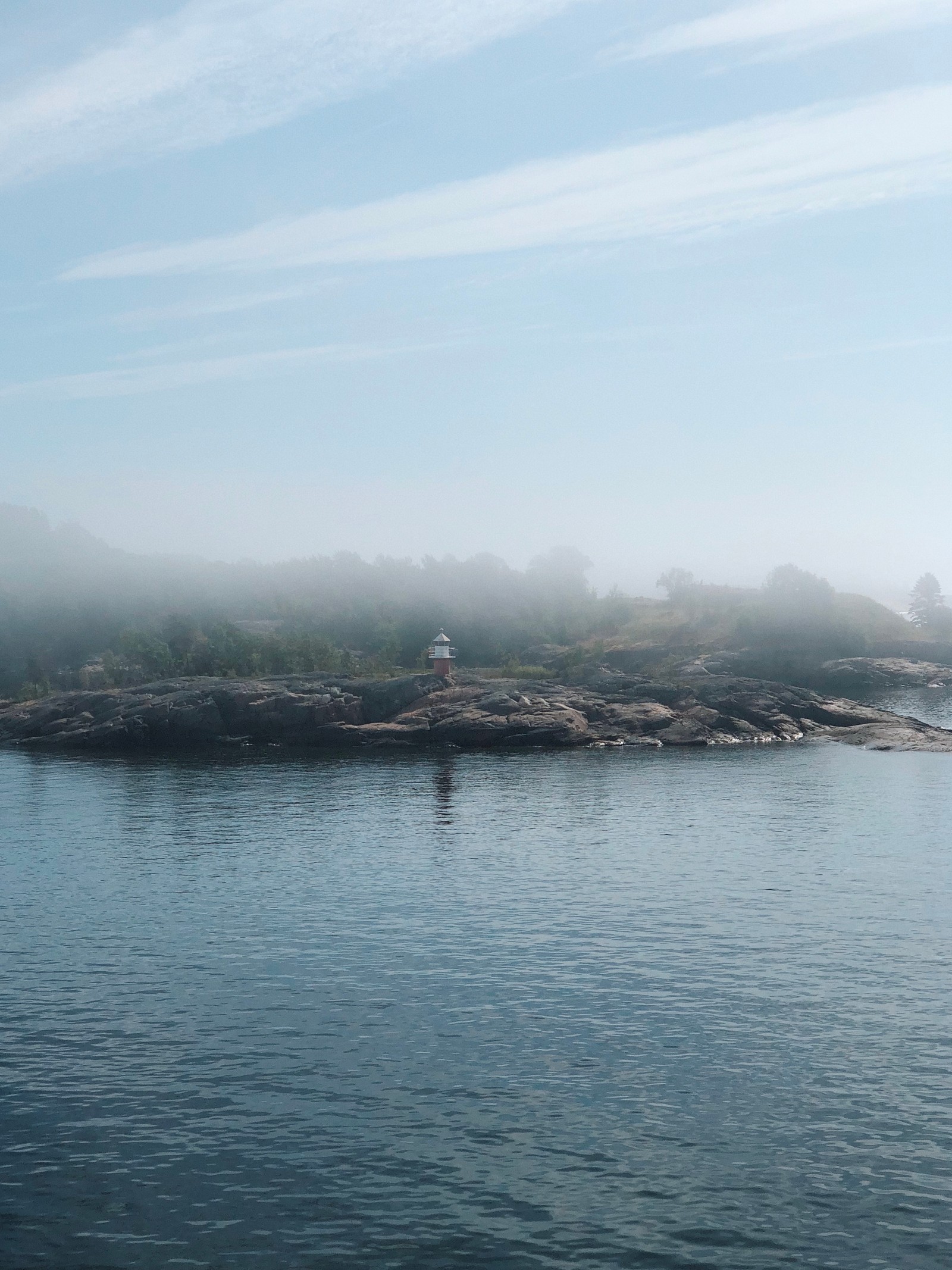 There is a small island with a lighthouse on top of it (liquid, water resources, atmosphere, fluid, bank)