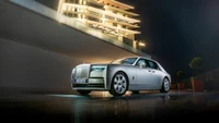 Impresionante Rolls Royce Phantom iluminado contra un edificio de lujo moderno