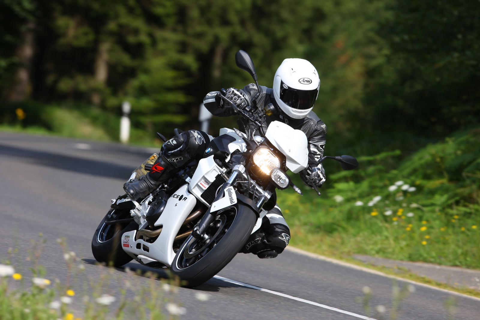 Un hombre montando una motocicleta por la carretera en un día soleado (motocicleta, motociclismo, casco, carreras de motos, bmw)