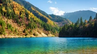 Lago sereno cercado por folhagem vibrante de outono e majestosas montanhas em um parque nacional.