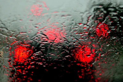 Gotas de chuva abstratas em vidro com bokeh vermelho