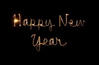 Handwritten Happy New Year in Golden Sparkler Light on Black Background