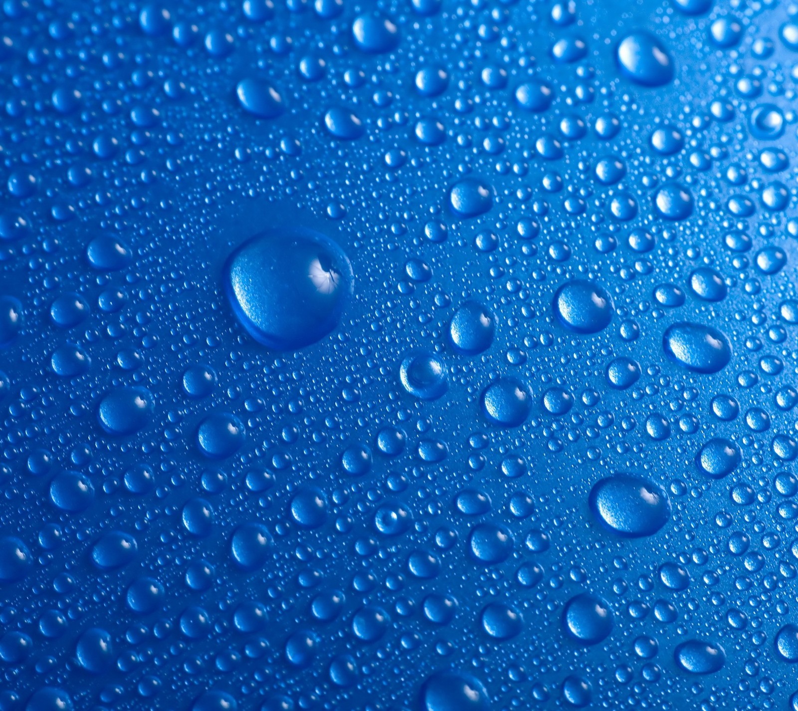 Un gros plan de gouttes d'eau sur une surface bleue (bleu, gouttes, eau)