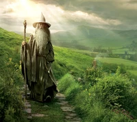 A wise figure with a long beard and staff walks along a lush, winding path in a serene landscape.