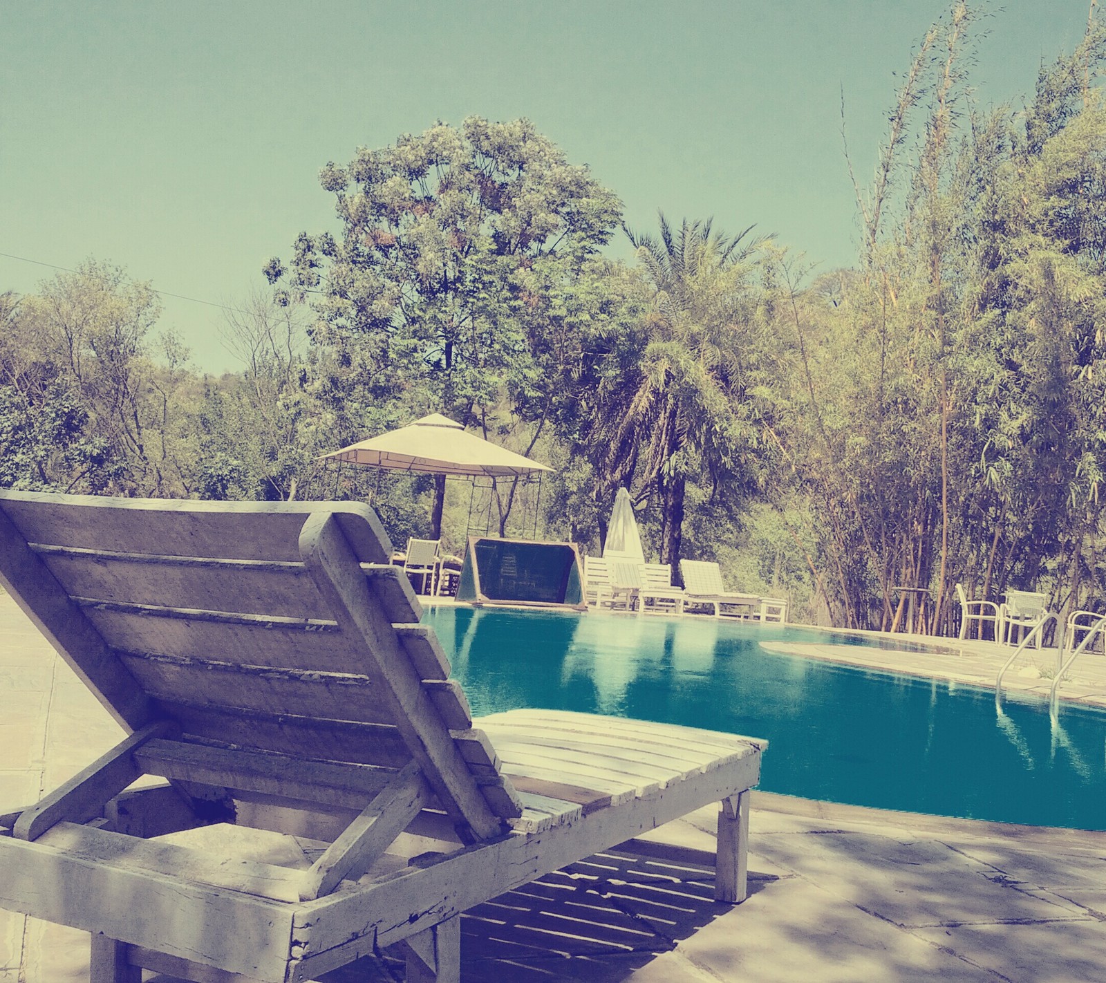 Há uma cadeira de madeira ao lado de uma piscina (legal, diversão, feriado, índia, india)