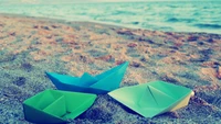 Colorful Paper Boats on Sandy Shoreline by Turquoise Sea