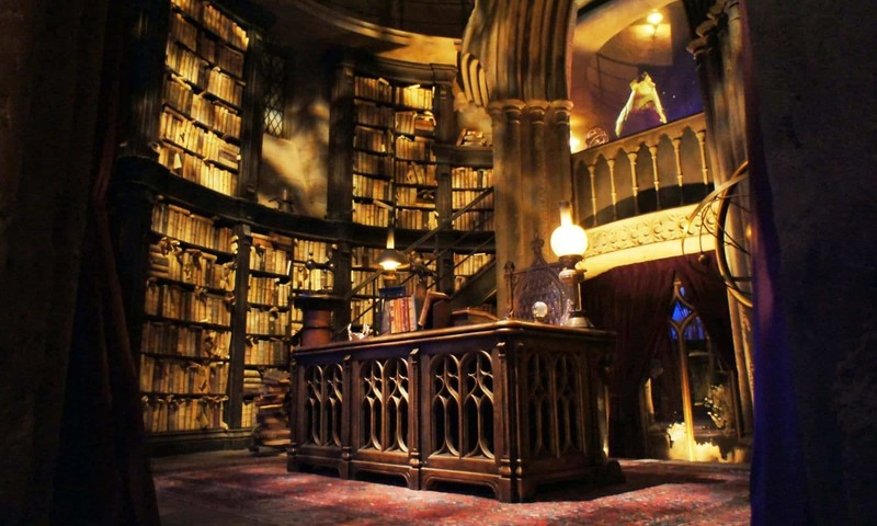 Une vue d'une bibliothèque avec un bureau et beaucoup de livres (professeur albus dumbledore, harry potter, bâtiment, cathédrale, métropole)