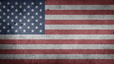 Weathered texture of the United States flag featuring red and white stripes with a blue canton adorned with white stars.