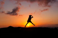 Silhouette alegre de una mujer saltando al amanecer