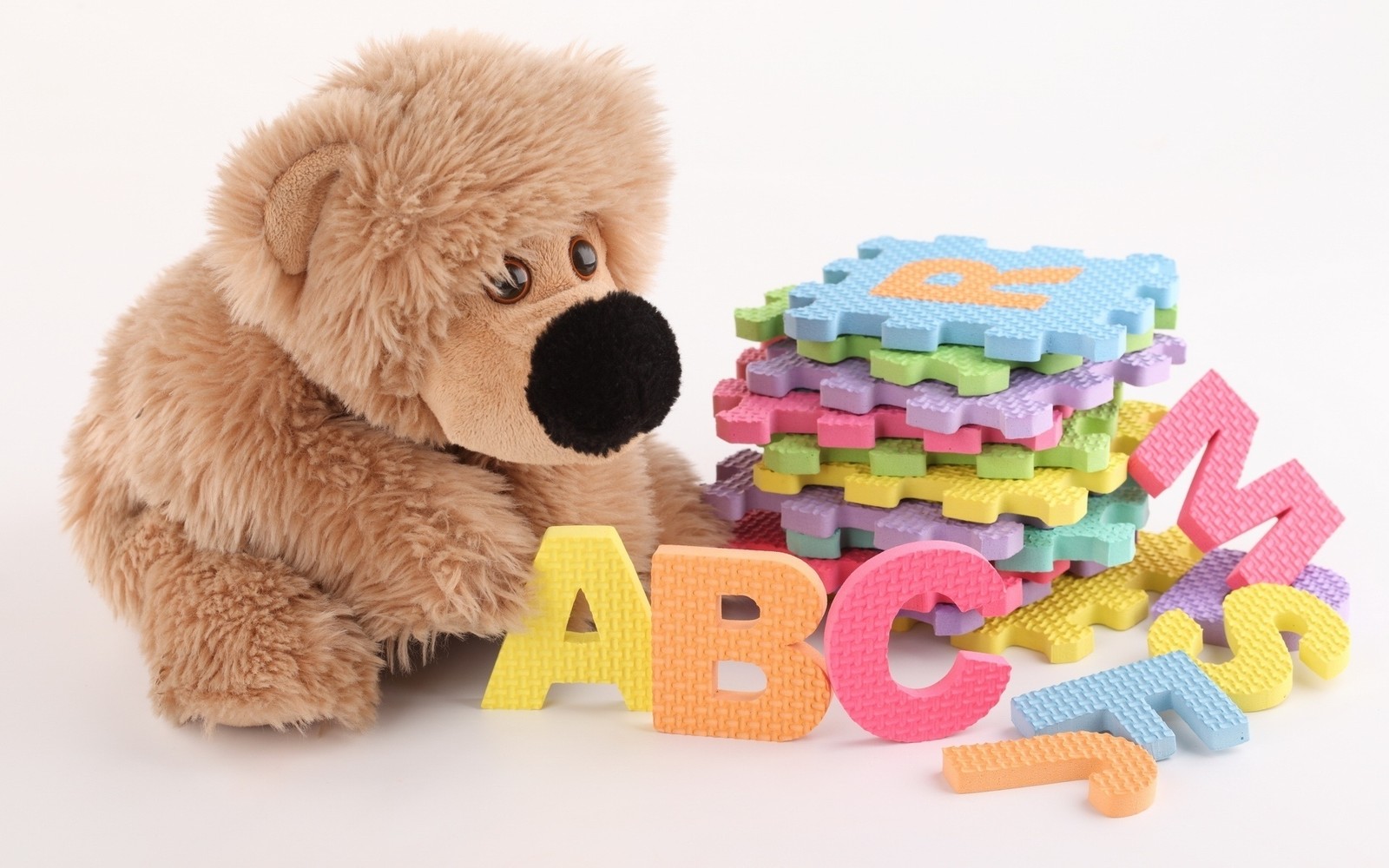 Ein teddy mit engelsflügeln sitzt neben einem haufen von buchstabenblöcken (stofftier, teddybär, plüsch, kind, material)