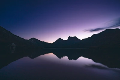 Paysage nocturne serein de Cradle Mountain reflété dans un lac tranquille sous un ciel violet