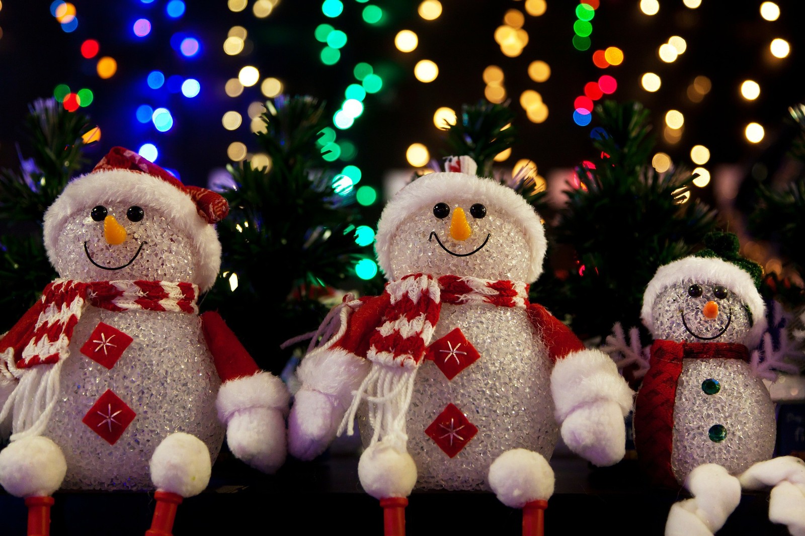 Tres muñecos de nieve están sentados uno al lado del otro en una mesa (día de navidad, muñeco de nieve, navidad, juguete, evento)