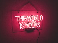 Glowing Neon Sign: The World Is Yours on a Red Background