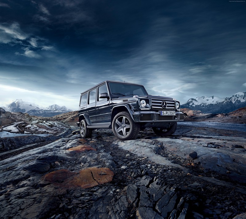 Arafed vehicle parked on rocky terrain with mountains in the background (black, car, g class, rock, sky)