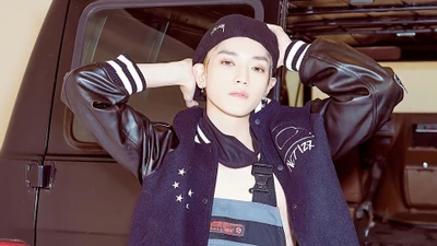 Taeyong of NCT 127 showcasing a stylish look in a varsity jacket against a vintage vehicle backdrop.