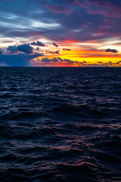 Coucher de soleil vibrant sur l'océan avec un ciel nuageux dramatique