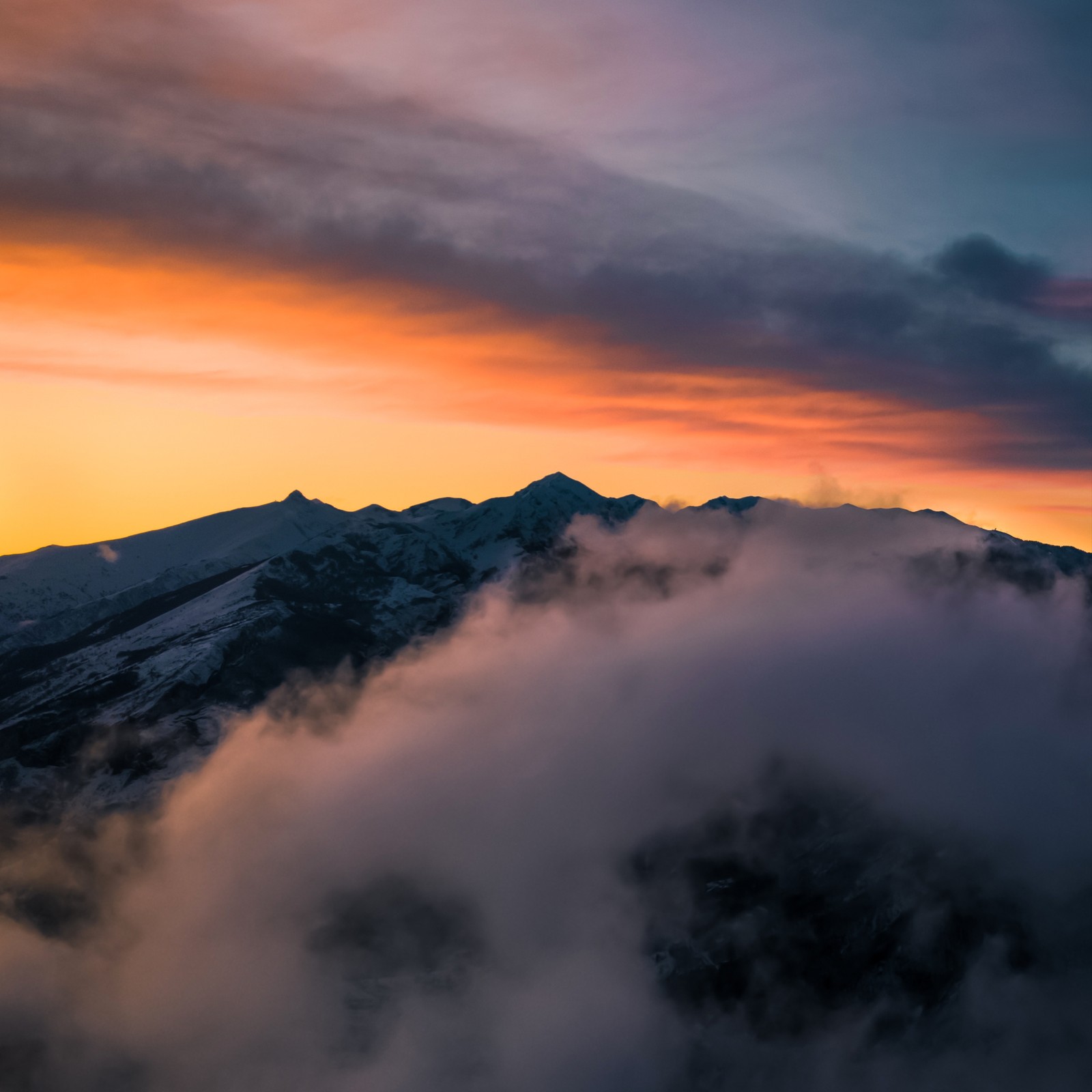 Arafed view of a mountain range with a sunset in the background (cloud, atmosphere, mountain, natural landscape, afterglow)