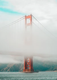 Golden Gate Bridge, der aus dem Nebel über ruhige Gewässer auftaucht