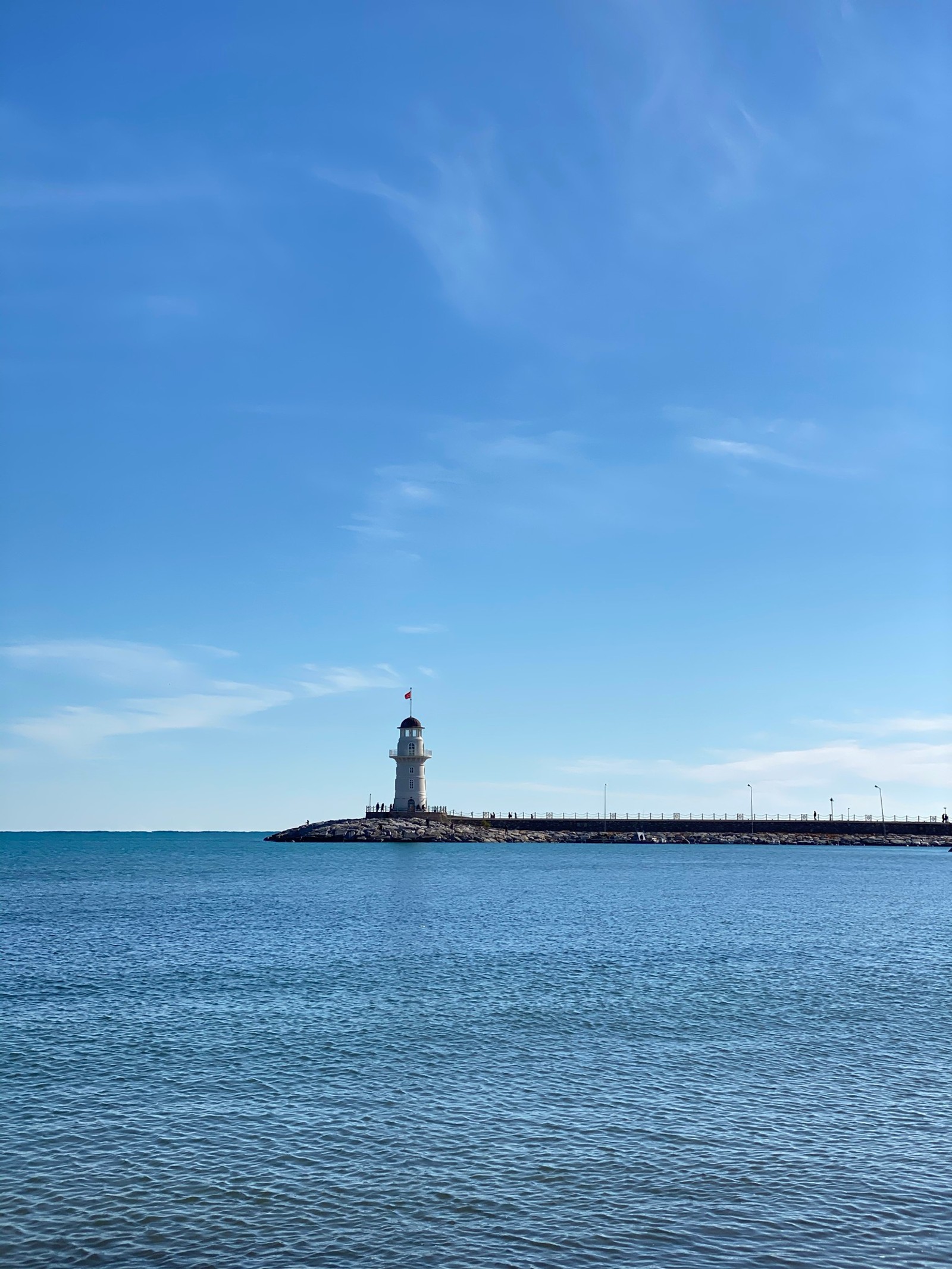 There is a lighthouse on the shore of a large body of water (cloud, water, lighthouse, tower, fluid)