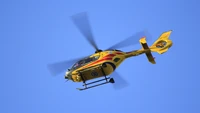 Helicóptero amarelo em voo contra um céu azul claro