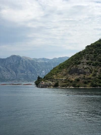 Gelassene Küstenansicht mit bergigem Hintergrund und ruhigem Wasser