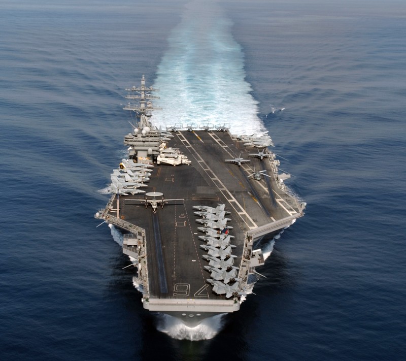 A view of a large aircraft carrier flying over the ocean (blue, navy, ship, water)