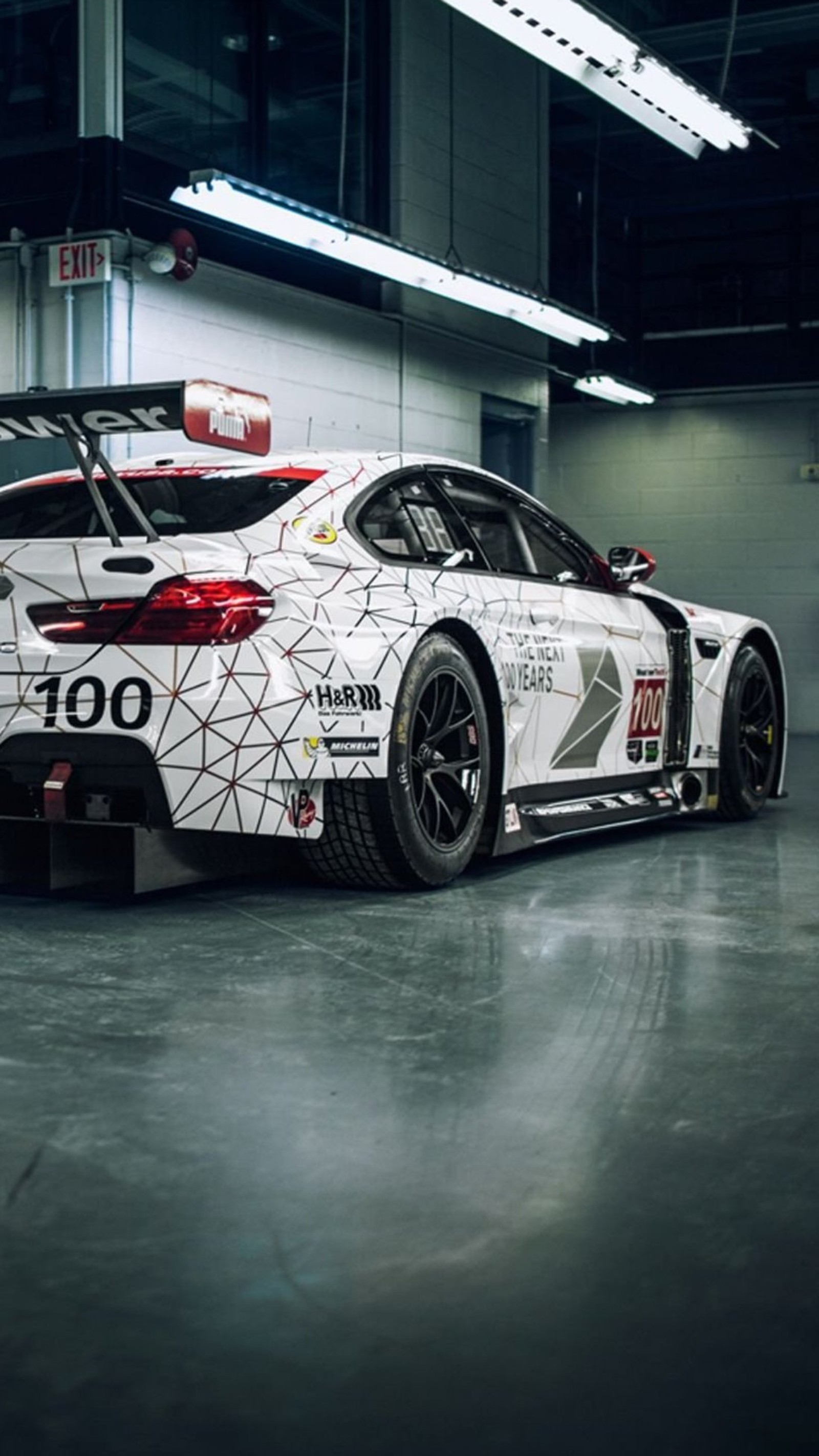 A close up of a white car in a garage with a black floor (bmw, car, race)