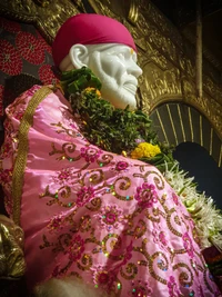 Göttliches Idol von Sai Baba, geschmückt mit rosa Gewändern und Blumenopfern