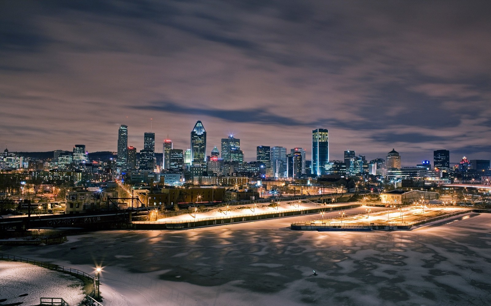 Vista de un horizonte de ciudad por la noche con un río congelado (paisaje urbano, ciudad, panorama, área urbana, metrópolis)