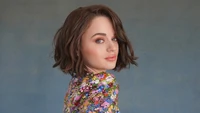 Joey King en un vibrante atuendo floral, mostrando elegancia y encanto en una sesión de fotos.