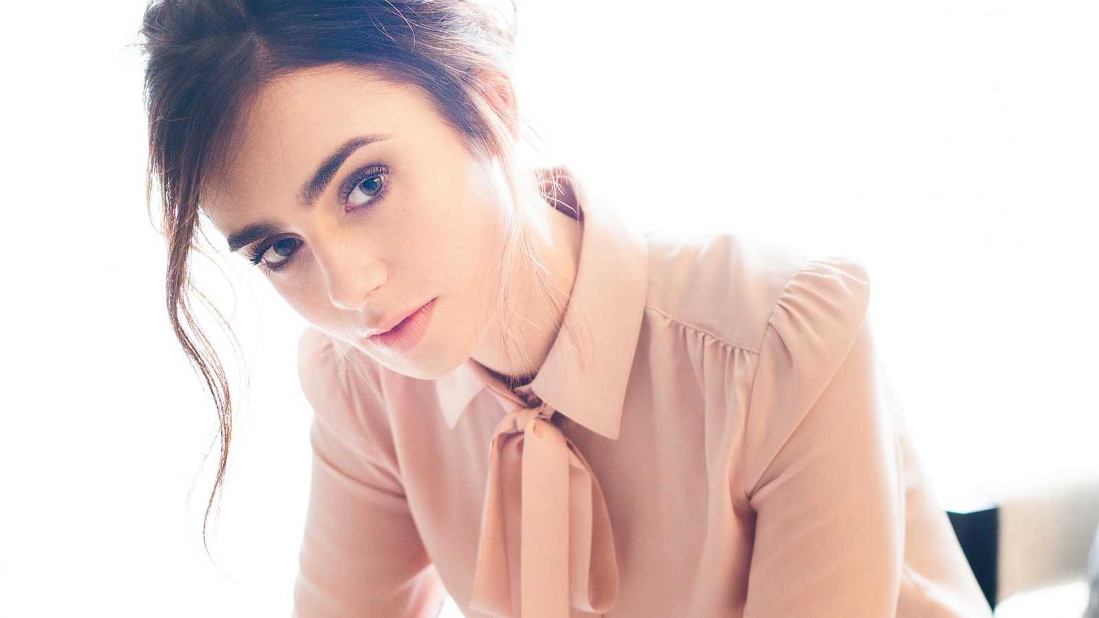 Une femme assise à une table avec un ordinateur portable (lily collins, actrice, femmes, filles, célébrité)