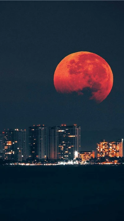 Roter Mond über der städtischen Skyline