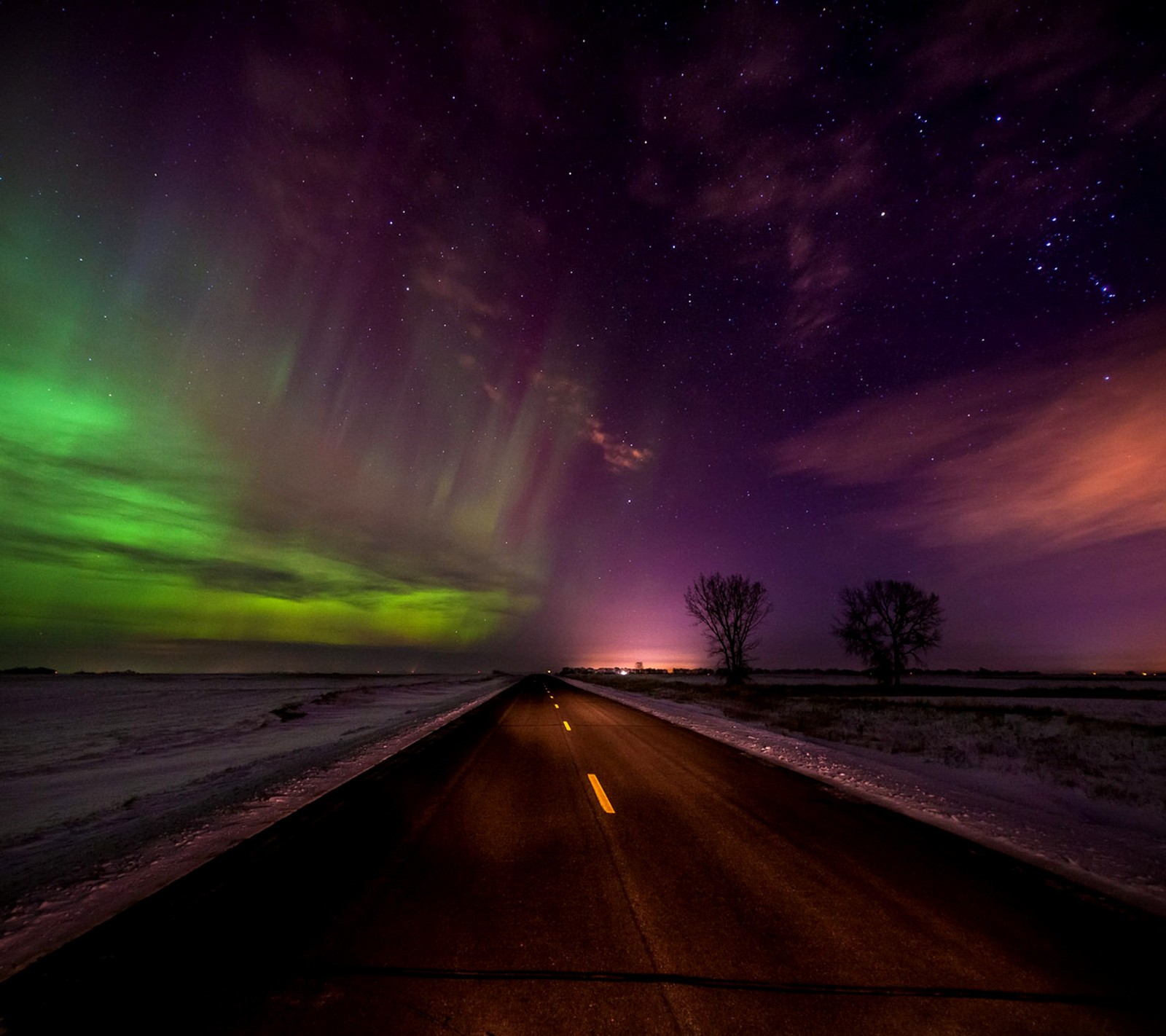 Una vista de una larga carretera con una aurora boreal brillante en verde y púrpura (aurora, borealis)