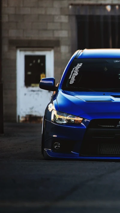 Mitsubishi Evo modificado em azul marcante, exibindo detalhes de tuning e uma postura agressiva.