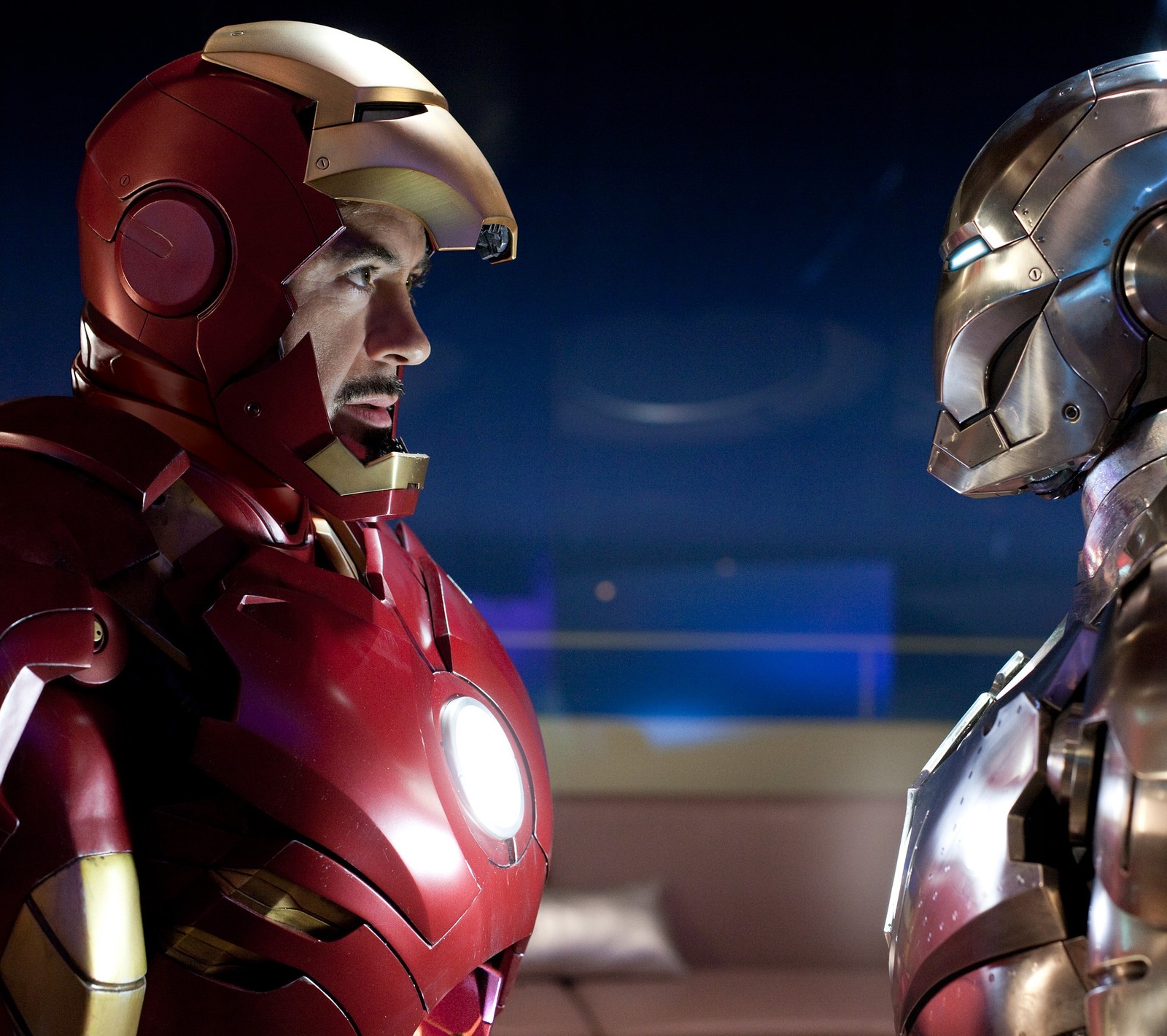 There are two iron man suits standing next to each other (iron, man)