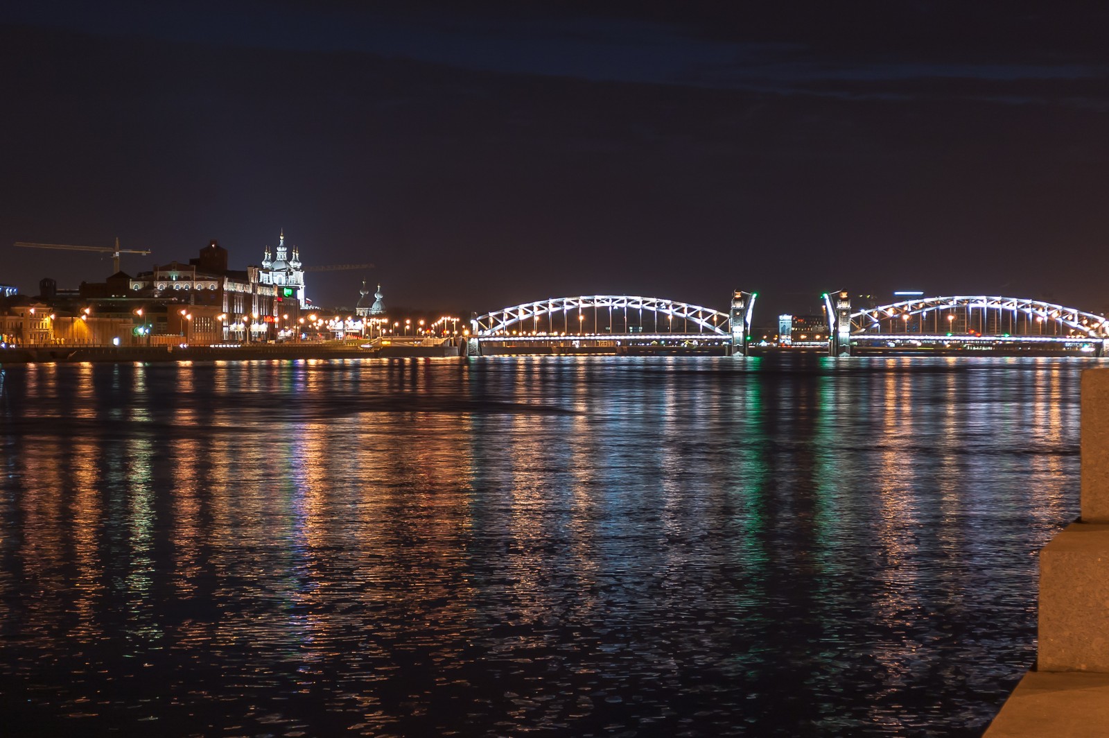 Vista noturna de uma ponte sobre um rio com uma ponte ao fundo (reflexo, paisagem urbana, noite, água, ponte)