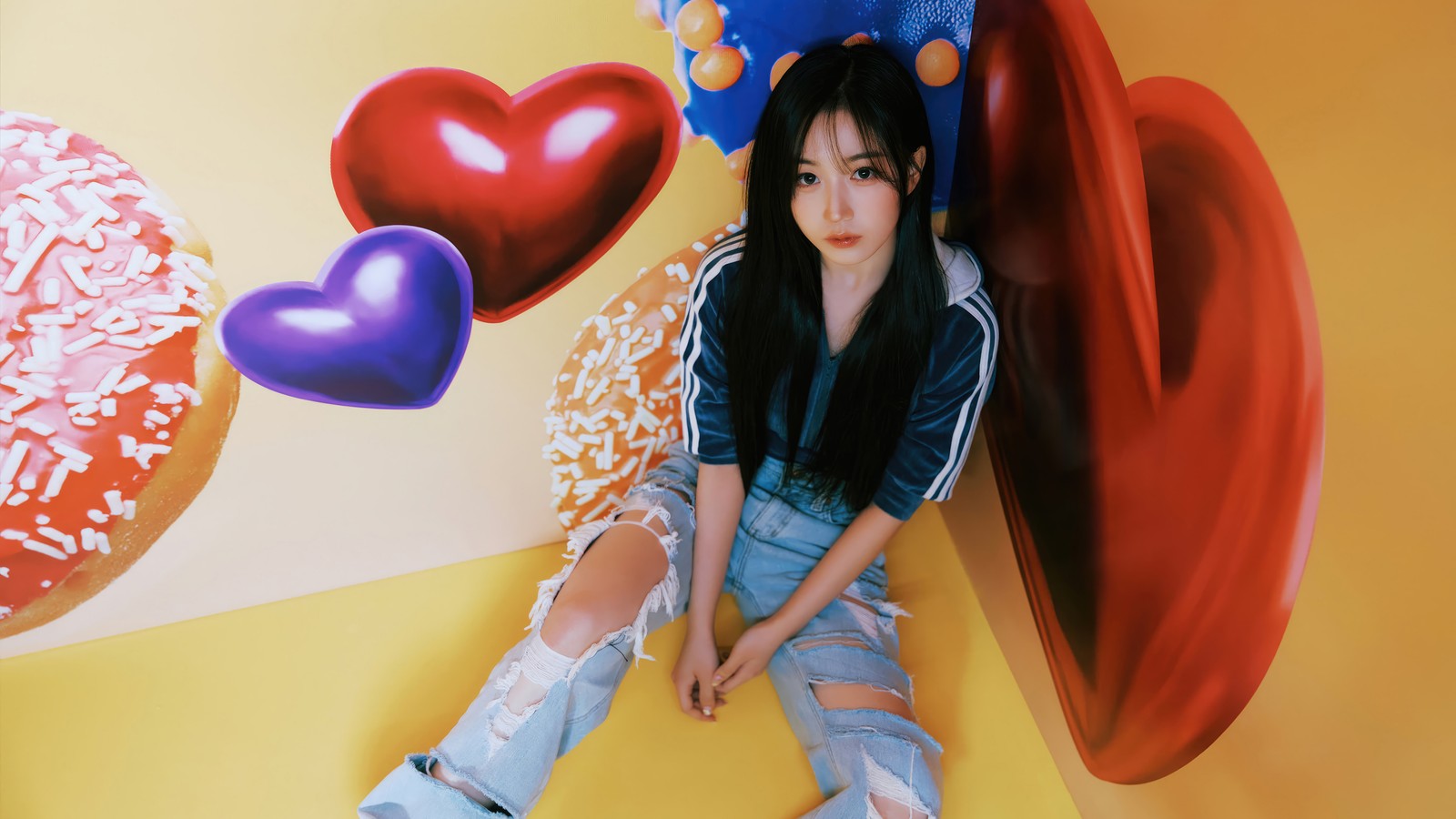 Una jirafa sentada en el suelo frente a una pared con un donut y un corazón (nmixx, kpop, k pop, chicas, grupo coreano de chicas)