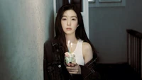 Irene from Red Velvet holding a birthday cake with candles, standing in a softly lit hallway.