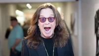 Ozzy Osbourne sonriendo con gafas de sol, mostrando un look divertido y a la moda durante su gira de despedida.