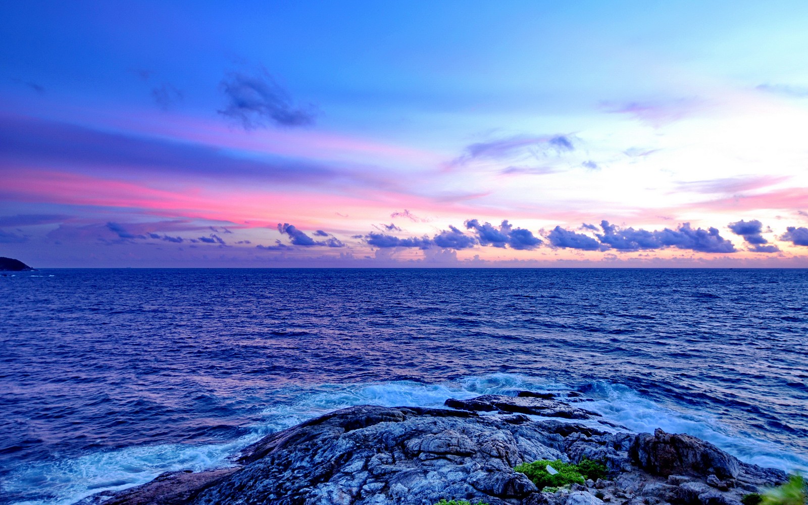 Una vista de un hermoso atardecer sobre el océano con rocas (promthep cape, phuket, tailandia, paisaje marino, costa rocosa)