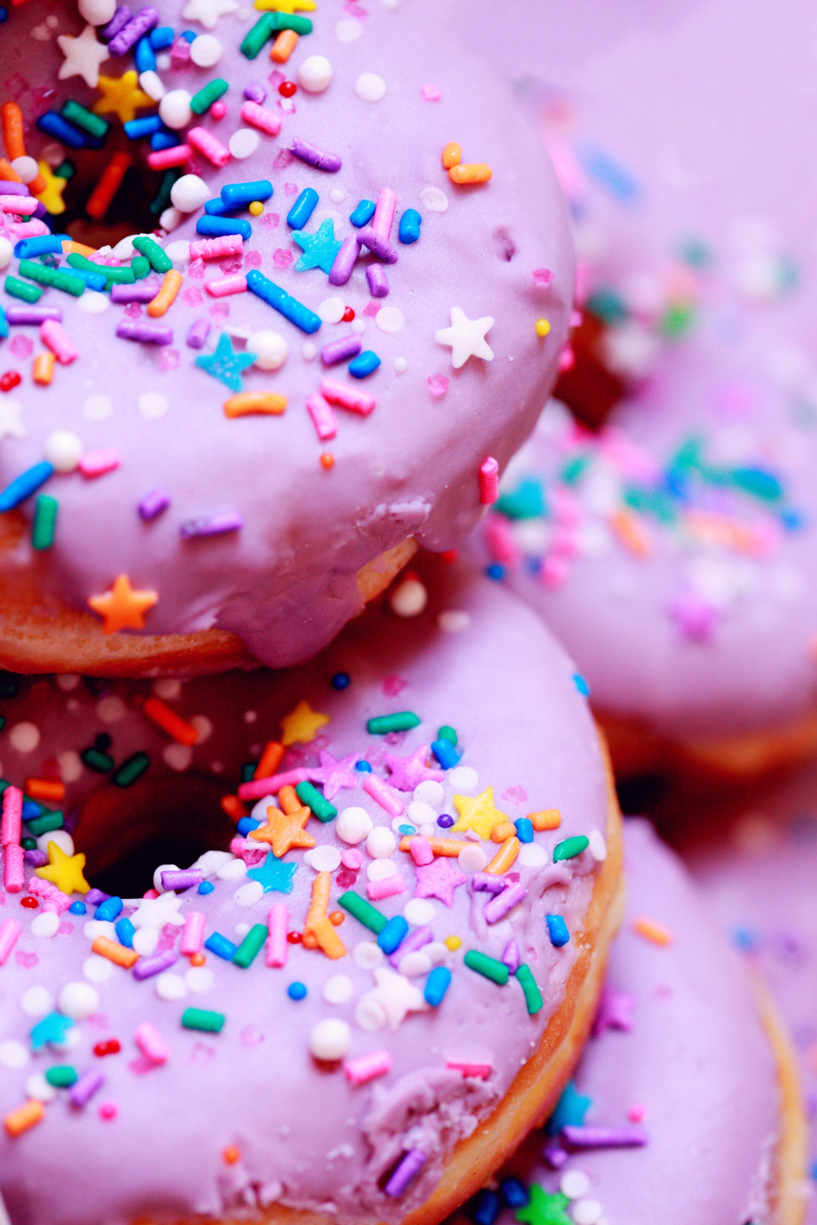 Hay muchos donuts cubiertos con glaseado rosa (cumpleaños, fiesta, aniversario de bodas, pastel, regalo)