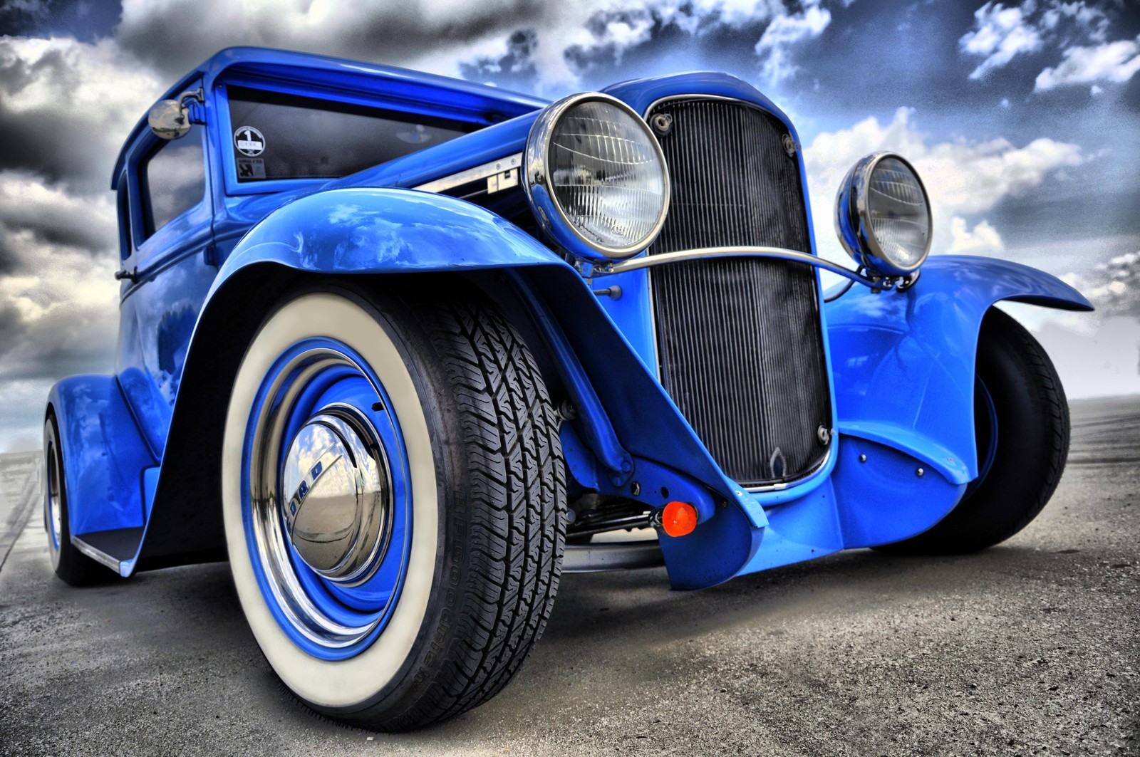 Eine nahaufnahme eines blauen autos, das unter einem bewölkten himmel auf der straße parkt (hot rod, auto, oldtimer, blau, klassisch)