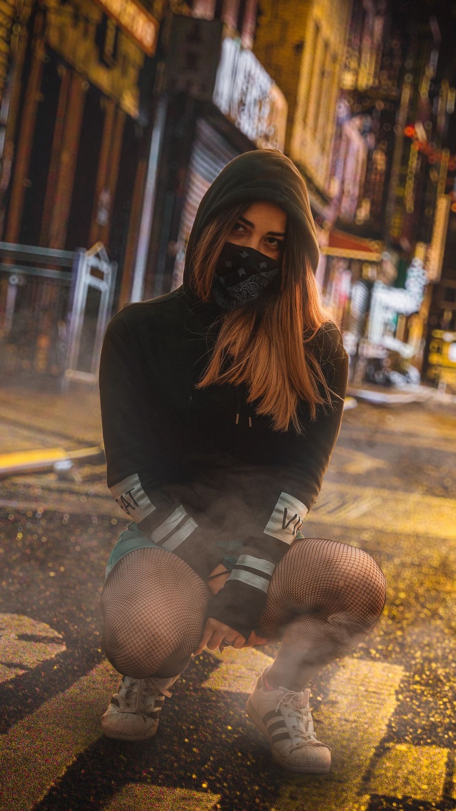 Image aérienne d'une femme accroupie dans la rue avec un hoodie noir (coronavirus, fille, hd, jeans, masque)