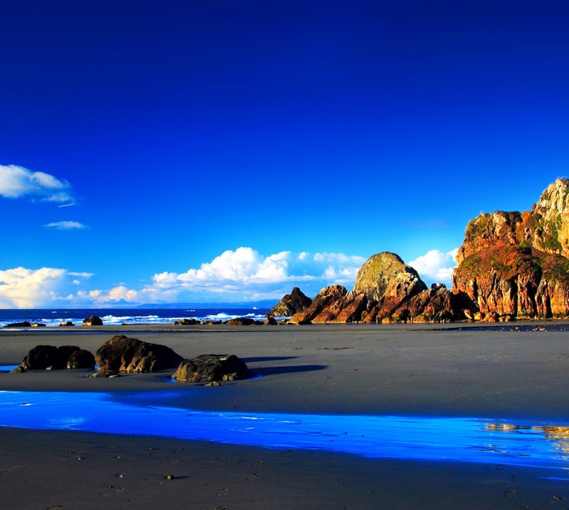 Es gibt einen blauen wasserstrom, der am strand hinunterfließt. (strand, natur)