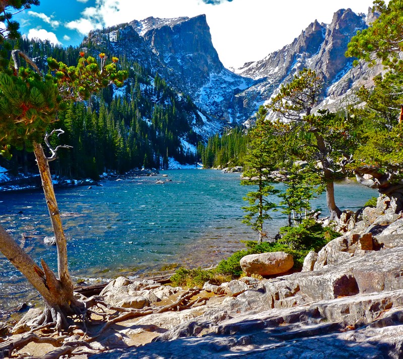 There is a man standing on a rock near a lake (hd, lake, mountain)