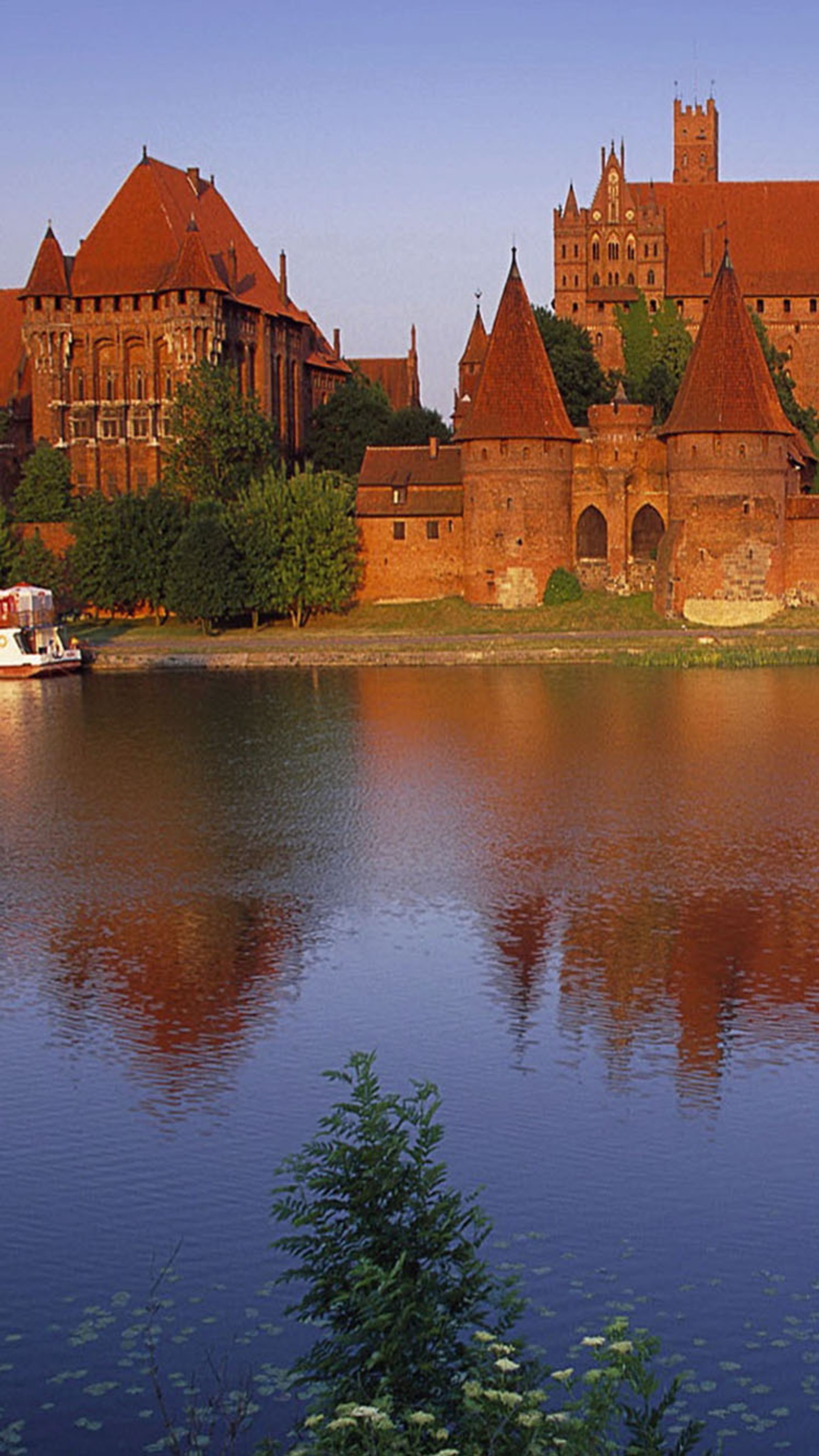 There is a boat that is floating in the water near a castle (castle, lake)