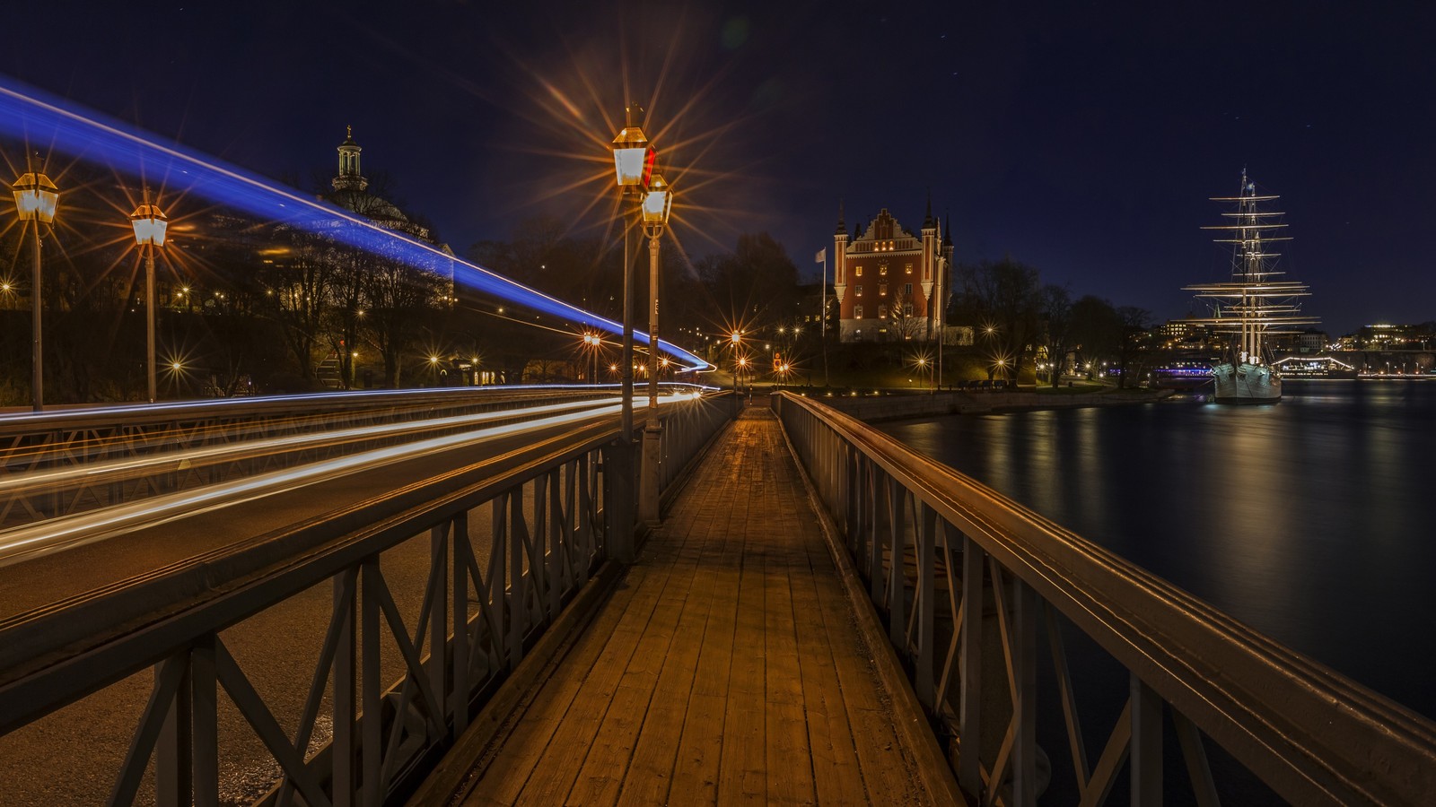 A view of a bridge with a long exposure of a city at night (reflection, water, light, building, infrastructure)